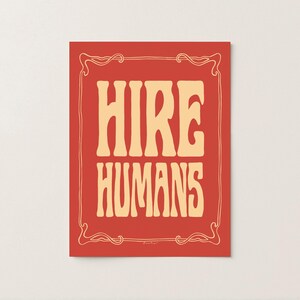 A yellow and red art print of the words HIRE HUMANS in a hand-lettered art nouveau style within a decorative art nouveau border.