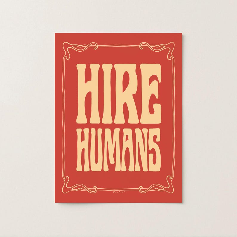 A yellow and red art print of the words HIRE HUMANS in a hand-lettered art nouveau style within a decorative art nouveau border.