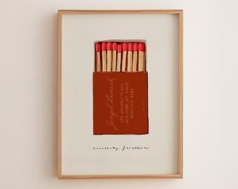 May include: A framed print featuring a matchbox with red-tipped matches. The box is rust-colored with text reading Joseph Leonard, 170 Waverly Place, New York, NY 10014, (646) 429-5383. Below the box, the text reads necessary friction.