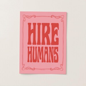 A red and pink art print of the words HIRE HUMANS in a hand-lettered art nouveau style within a decorative art nouveau border.