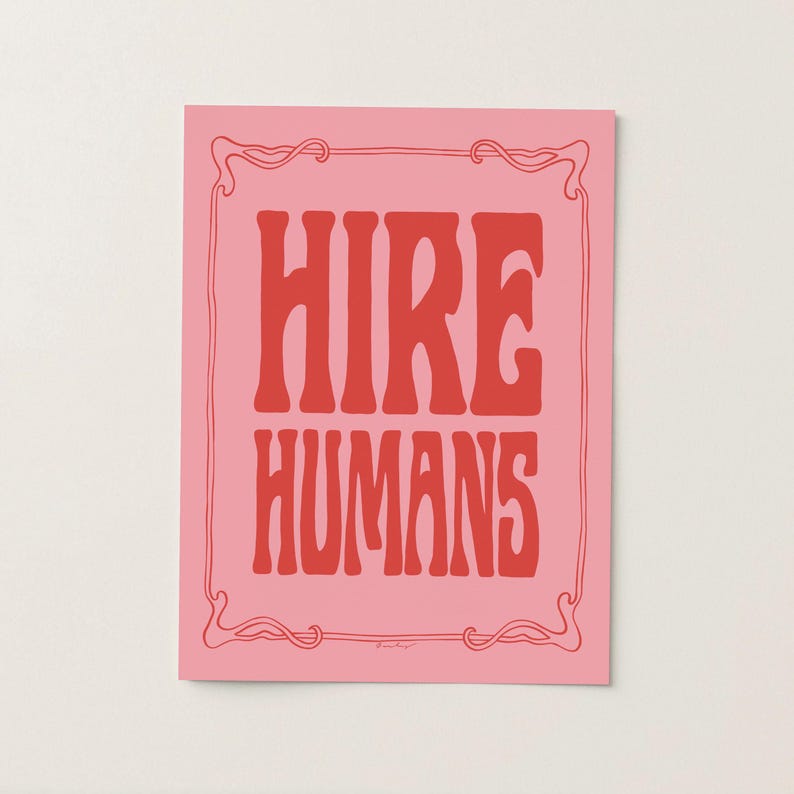 A red and pink art print of the words HIRE HUMANS in a hand-lettered art nouveau style within a decorative art nouveau border.