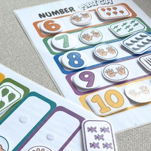 May include: A Number Match educational activity sheet featuring colorful rectangular rows and circular tokens. The sheet displays numbers 6 through 10, with corresponding illustrations of hands, balloons, candies, and teddy bears attached via velcro.