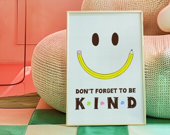 Könnte beinhalten: Ein gerahmter Kunstdruck mit einem lächelnden Gesichtsdesign. Das Lächeln ist ein gelber Bleistift, und die Augen sind braune Ovale. Der Text "DON'T FORGET TO BE KIND" steht unter dem Gesicht, mit farbigen Akzenten auf dem Wort KIND. Der Hintergrund ist rosa.