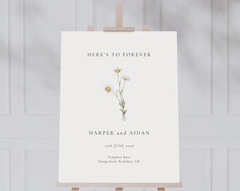 Op de afbeelding: Een wit bord met de tekst "HERE'S TO FOREVER" bovenaan, gevolgd door een aquarel-illustratie van een boeket witte madeliefjes. Onder de illustratie staat de tekst "HARPER en AIDAN", "13th JUNE 2016", "Templars Barn" en "Hungerford, Berkshire, UK".