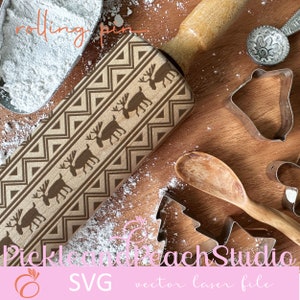 May include: A wooden rolling pin with a brown and beige geometric pattern and reindeer silhouettes. The rolling pin is on a wooden surface with white powder and cookie cutters.