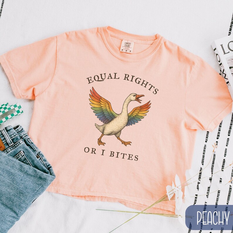 Peut inclure: T-shirt p&ecirc;che avec l'inscription "EQUAL RIGHTS OR I BITES" et un dessin d'oie aux ailes arc-en-ciel. Le t-shirt est en tissu doux, id&eacute;al pour un usage d&eacute;contract&eacute;.