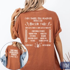 K&ouml;nnte beinhalten: Ein rostfarbenes T-Shirt mit wei&szlig;em Text, der "Functional Neurological Disorder World Tour" lautet und verschiedene Symptome auflistet. Der Text lautet auch "Some days I rock it. Some days it rocks me. Either way we're rockin'."