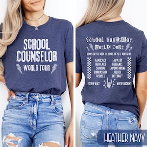 K&ouml;nnte beinhalten: Ein heidefarbenes marineblaues T-Shirt mit dem Aufdruck "School Counselor World Tour" auf Vorder- und R&uuml;ckseite. Die R&uuml;ckseite des Shirts enth&auml;lt au&szlig;erdem den Text "Some days I rock it. Some days it rocks me." und eine Liste von W&ouml;rtern, darunter "Advocacy", "Outreach", "Support", "Compassion", "Respect", "Empathy", "Guidance", "Empowerment", "Justice" und "Integrity".