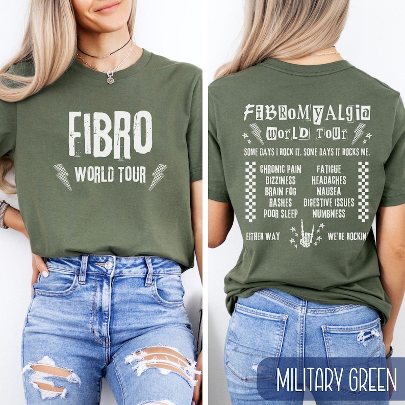 May include: A green t-shirt with the text "FIBRO WORLD TOUR" on the front and "FIBROMYALGIA WORLD TOUR" on the back. The back also includes a list of symptoms associated with fibromyalgia, including chronic pain, dizziness, brain fog, rashes, poor sleep, fatigue, headaches, nausea, digestive issues, and numbness. The text on the shirt is white and the background is military green.