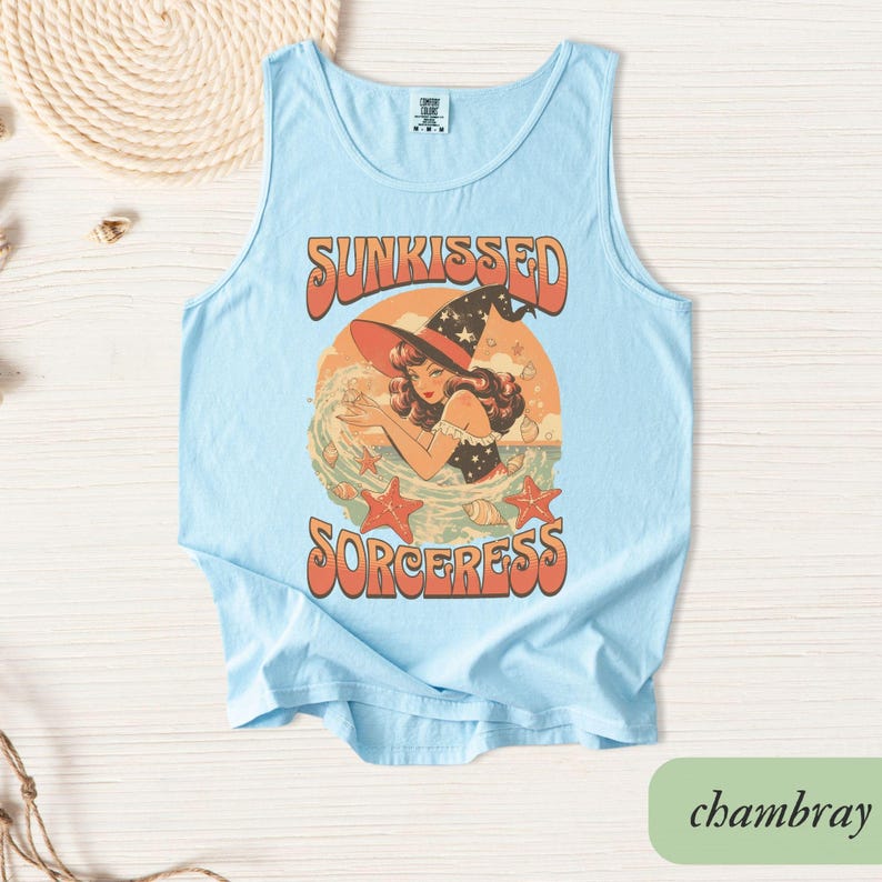 May include: Light blue tank top with a retro graphic of a woman in a witch hat, the text "SUNKISSED SORCERESS", and starfish. The shirt is made of a soft material.