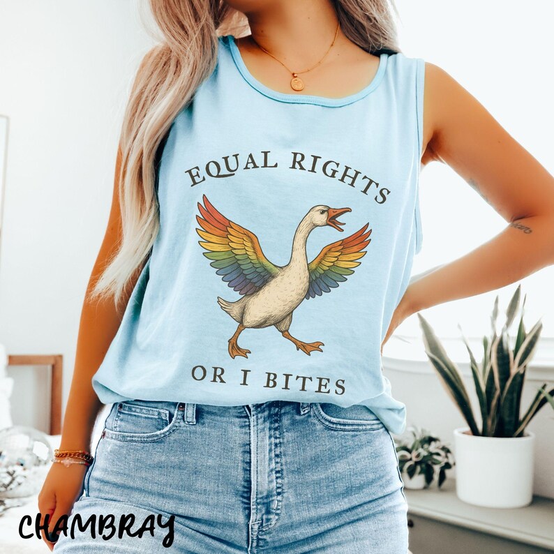 Puede incluir: Camiseta sin mangas azul claro con el texto "EQUAL RIGHTS OR I BITES" y un dibujo de un ganso con alas de arco&iacute;ris. La camiseta se combina con vaqueros azules.