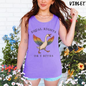 Puede incluir: Una camiseta sin mangas violeta con el texto "EQUAL RIGHTS OR I BITES" y un gr&aacute;fico de un ganso con alas de arco&iacute;ris. La camiseta sin mangas es sin mangas y est&aacute; hecha de un material suave.