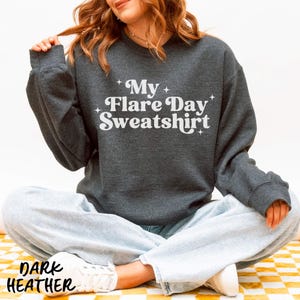 May include: Dark heather gray sweatshirt with the text "My Flare Day Sweatshirt" in white. The sweatshirt is a crew neck style. The words "Dark Heather" are printed at the bottom of the image.
