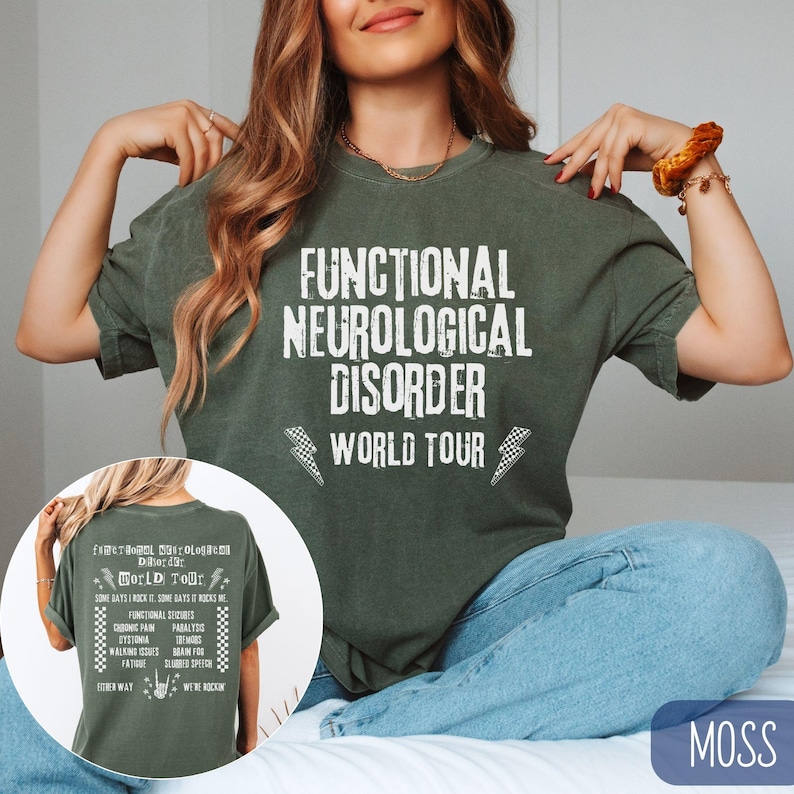 K&ouml;nnte beinhalten: Ein gr&uuml;nes T-Shirt mit dem Aufdruck "Functional Neurological Disorder World Tour" auf der Vorderseite. Der Text ist in einer wei&szlig;en, abgenutzten Schriftart gehalten. Das Shirt wird von einer Person getragen.