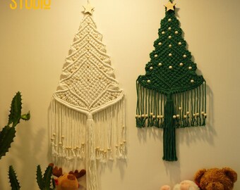 Könnte beinhalten: Zwei Makramee-Weihnachtsbaum-Wandbehänge, einer weiß und einer grün, mit Holzperlen und einem Stern oben.