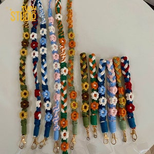 May include: Assortment of colorful braided phone straps with floral and sunflower designs. Each strap has a gold metal clasp.