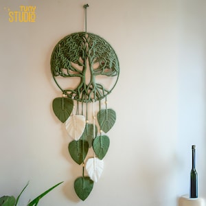 May include: Green macrame wall hanging with a tree of life design and white and green leaf accents.