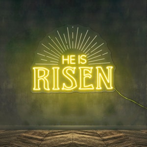 May include: Yellow neon sign with a sunburst design and the words "He is Risen" on a dark green wall.