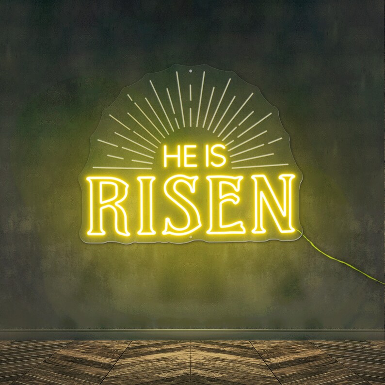 May include: Yellow neon sign with a sunburst design and the words "He is Risen" on a dark green wall.