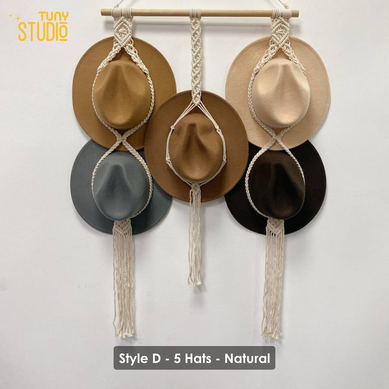 May include: Five hats hanging on a macrame hat rack with a wooden dowel. The hats are brown, beige, gray, and black. The macrame is natural colored. The text "Style D - 5 Hats - Natural" is at the bottom of the image.
