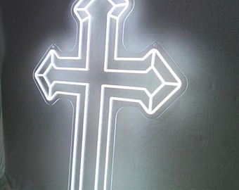 May include: A white neon cross sign with a geometric design. The sign is illuminated and mounted on a gray surface. The text "TUNY STUDIO" is in the upper left corner.