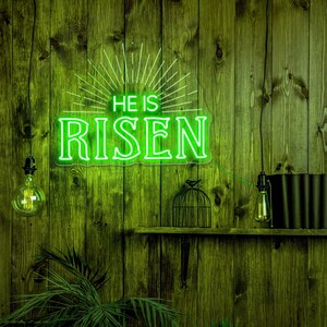 May include: Green neon sign with the words "He is Risen" on a wooden wall with two light bulbs hanging from the ceiling and a birdcage on a shelf.