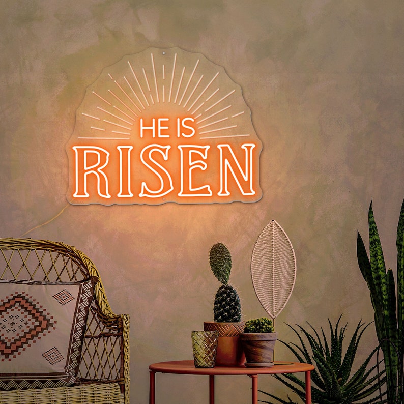May include: A neon sign with a white outline and orange glow reads "He is Risen" with a sunburst design behind the text.