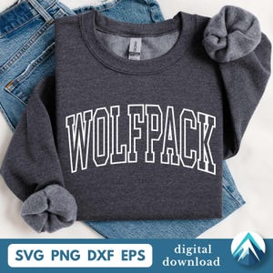 Pode incluir: Um moletom cinza escuro com a palavra "WOLFPACK" em letras brancas. O moletom está colocado sobre jeans azuis. A parte inferior da imagem inclui o texto "SVG PNG DXF EPS" e "download digital".