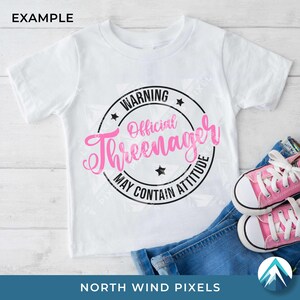 K&ouml;nnte beinhalten: Wei&szlig;es T-Shirt mit Rundhalsausschnitt und einem rosa-schwarzen Aufdruck mit der Aufschrift "WARNING Official Threenager MAY CONTAIN ATTITUDE". Das Shirt wird mit blauen Jeans und rosa Turnschuhen gezeigt.