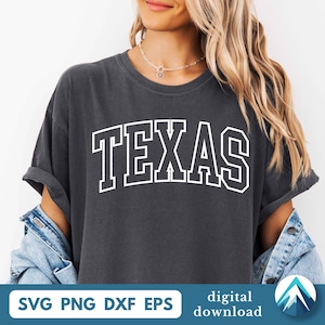 May include: A charcoal gray short-sleeve t-shirt featuring the word TEXAS in a large, white, arched collegiate-style font across the chest. The shirt has a crew neckline and rolled sleeves, with a denim jacket layered over the shoulders.