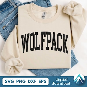 Puede incluir: Una sudadera de color crema con la palabra "WOLFPACK" en letras negras y audaces, arqueadas. La sudadera está doblada sobre unos vaqueros azules. La parte inferior de la imagen incluye el texto "SVG PNG DXF EPS" y "descarga digital".