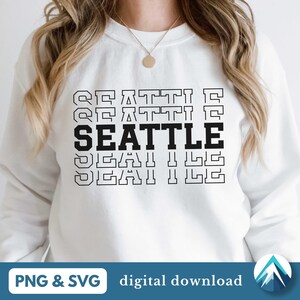 Puede incluir: Sudadera blanca con la palabra "SEATTLE" impresa en letras negras, con la palabra "SEATTLE" repetida en un tamaño de fuente más pequeño arriba y debajo de la palabra principal.