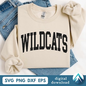 May include: A cream-colored sweatshirt with the word "WILDCATS" in bold, black, arched lettering. The sweatshirt is laid on top of blue denim jeans. The bottom of the image includes the text "SVG PNG DXF EPS" and "digital download".