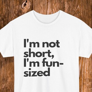 Pode incluir: Camiseta branca com texto preto que diz "Eu não sou baixo, eu sou do tamanho divertido".