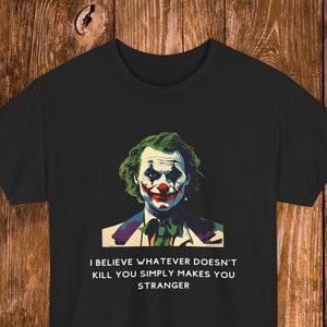 May include: Black t-shirt with a colorful image of the Joker from the movie "The Dark Knight". The text "I believe whatever doesn't kill you simply makes you stranger" is printed below the image.