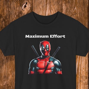 Könnte beinhalten: Schwarzes T-Shirt mit einem roten und schwarzen Deadpool-Charakter-Motiv und dem Text "Maximum Effort" in Weiß.