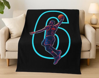 May include: Black and blue throw blanket with a graphic of a basketball player dunking a basketball through a neon blue number six. The player is wearing a red and white jersey with the name "James" and the number "6" on the back.