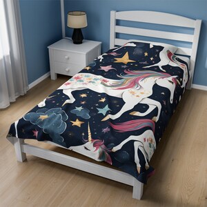 May include: A navy blue twin-sized bedspread with a white unicorn and stars pattern. The unicorn has a rainbow mane and tail. The stars are gold and white.