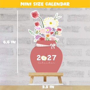 May include: A mini size 2027 calendar featuring a pink vase filled with a colorful floral bouquet. The calendar measures 6.6 inches in height and 3.5 inches in width, resting on a small wooden stand. The text 2027 Calendar is printed on the vase.