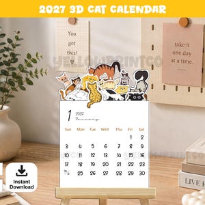 Puede incluir: Un calendario de escritorio 2027 con una página blanca para enero que muestra texto y números en negro. La parte superior del calendario está decorada con una colección de recortes de gatos ilustrados y coloridos en varias poses, con patrones naranjas, negros y blancos.