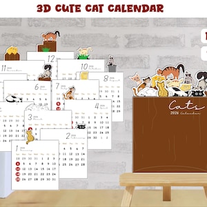 May include: A 3D cat calendar for 2026. The calendar features a wooden stand with a brown surface and a collection of illustrated cats. Each month is displayed on a separate white card with red dates and cat-themed illustrations. The text "3D CUTE CAT CALENDAR" is at the top.