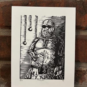 Könnte beinhalten: Ein schwarz-weißer Linoldruck auf Papier, der eine stilisierte Figur mit umwickeltem Kopf, dunkler Brille und strukturiertem Oberkörper zeigt. Links sind drei hängende Haken abgebildet. Der Text "Butterball" steht unten in der Mitte.