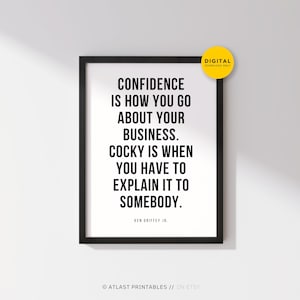 May include: A framed print with the quote "CONFIDENCE IS HOW YOU GO ABOUT YOUR BUSINESS. COCKY IS WHEN YOU HAVE TO EXPLAIN IT TO SOMEBODY." in black text. A yellow circle with "DIGITAL DOWNLOAD ONLY" is in the top right corner.