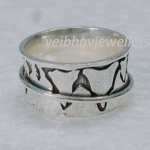 Peut inclure: Une bague spinner argentée avec un motif texturé. La bague comporte une bande centrale qui tourne librement, avec un motif de formes abstraites. La bague est probablement en argent sterling et est conçue pour un usage quotidien.