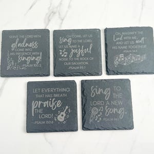May include: Five square slate coasters with engraved religious quotes and musical notes. The quotes include "Serve the Lord with gladness", "Sing to the Lord", and "Let everything that has breath praise the Lord!"