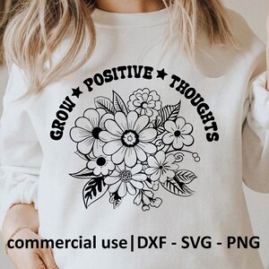 May include: White sweatshirt featuring a floral design with the words "GROW POSITIVE THOUGHTS" in a curved arch. The design includes various flowers and leaves in black. The bottom of the sweatshirt has the text "commercial use | DXF - SVG - PNG".