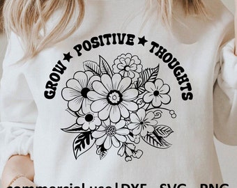 Pode incluir: Camisola branca com um design floral preto e a frase "GROW POSITIVE THOUGHTS" em arco. O design inclui várias flores e folhas. A parte inferior da camisola tem o texto "commercial use | DXF - SVG - PNG".