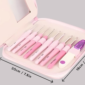 May include: A set of pink crochet hooks in a matching case. The case is open, displaying several crochet hooks in different shades of pink. The case measures 20cm wide and 18cm tall.