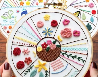 May include: A white embroidery hoop with a variety of colorful embroidery stitches and designs. The hoop is divided into sections, each featuring a different stitch, such as a back stitch, a satin stitch, and a French knot. The designs include flowers, leaves, and a basket of flowers.