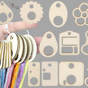 Op de afbeelding: Houten draadorganizers in verschillende vormen, waaronder druppels, cirkels en bloemen. De organizers zijn verbonden met een ring en kleurrijk borduurgaren. De afbeelding toont ook individuele houten vormen.